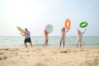 Tatilde, aile üyeleri gün içinde deniz kenarında dururken havaya şişirilebilir yüzükler fırlatıp zıplıyorlar.