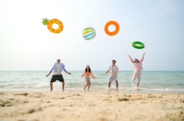 Tatilde, aile üyeleri gün içinde deniz kenarında dururken havaya şişirilebilir yüzükler fırlatıp zıplıyorlar.