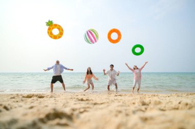 Tatilde, aile üyeleri gün içinde deniz kenarında dururken havaya şişirilebilir yüzükler fırlatıp zıplıyorlar.