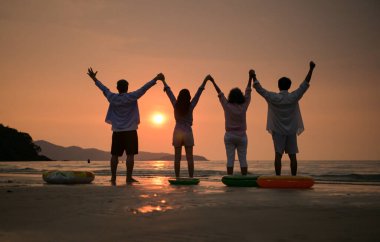 Gün batımında kumsalda el ele tutuşan mutlu aile manzarası. Birlikte huzurlu deniz kenarındaki anın tadını çıkarıyoruz. Birlik, sevgi ve aile yaşam tarzının sembolü.
