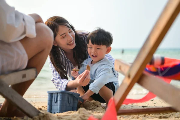 Tatilde, ebeveynler plaj sandalyelerinde oturup, gün boyunca çocuklarının kumsalda kum oyuncaklarıyla oynamasını seyrederler.