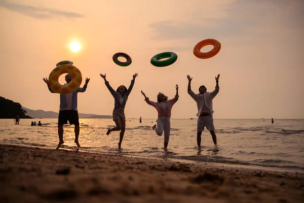 Gün batımında aile zıplıyor ve sahilde oynuyor, siluetler ıslak kumu yansıtıyordu, yaz yolculuğunu, özgürlüğü ve birlikte neşeli deniz hayatı kutluyorlardı.