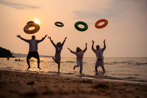 Gün batımında aile zıplıyor ve sahilde oynuyor, siluetler ıslak kumu yansıtıyordu, yaz yolculuğunu, özgürlüğü ve birlikte neşeli deniz hayatı kutluyorlardı.