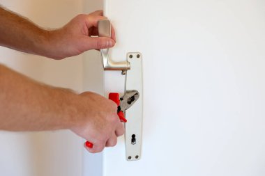 Erkek eller kapı kolu ve kilit mekanizmasını tamir etmek için kerpeten kullanıyor. Ev bakımı ve arama çalışmalarını yakından izliyorlar..