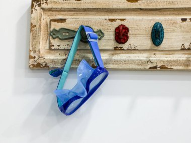 Havuz başında bir soyunma odasında, bir dalış maskesi antik bir ahşap askıya asılır, su sporlarını sembolize eder, aktif bir yaşam tarzı, sağIık ve modern fitness kültürü..