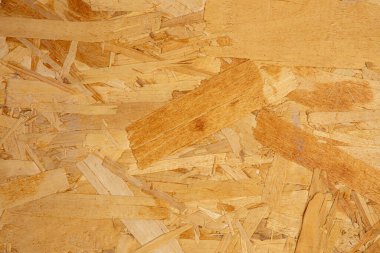 Doğal OSB dokusuna sahip ahşap parçacık arka planı, çevre dostu tasarım ve mobilyalar için geri dönüştürülmüş kereste taneleri. Profesyonel arka planlar için sağlam tahta yonga deseni ideal.