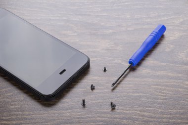 Telefon tamiri. Ekstra yedek parçalar. Tornavida ile kırmızı kalem.