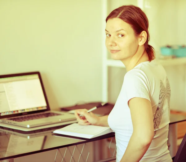 The girl in a white shirt sits at a table with a computer. Retro effect.