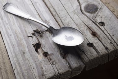 Eski püskü eski ahşap bir masa üzerinde metal bir kaşık. Köylü hayat.