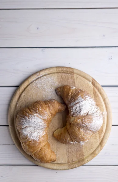 Fresh golden croissants on white wooden table. Country style. — Stock Photo, Image