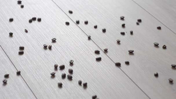 Coffee beans spilled on a beautiful wooden floor. Falling coffee beans backlit. Reverse. — Stock Video