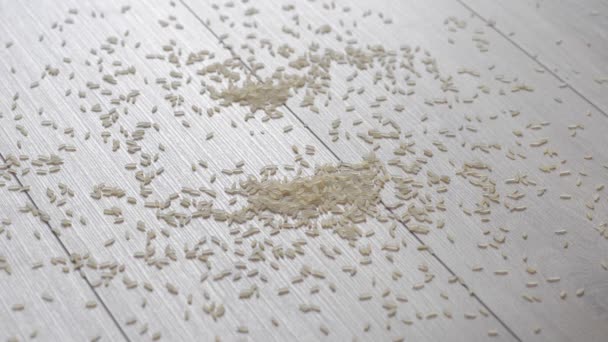 Crumbly rice spilled on a beautiful wooden floor. Falling rice backlit. Reverse. — Stock Video