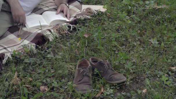 Ein gutaussehender Mann mit einem Buch im Gras. — Stockvideo
