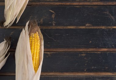 Olgun sarı Mısır karanlık eski ahşap bir masa üzerinde. Ülke stil.