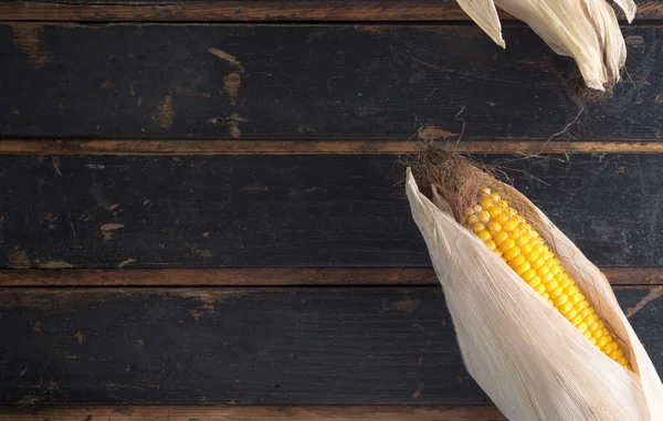 Ripe yellow corn on a dark old wooden table. Country style. — Stock Photo, Image