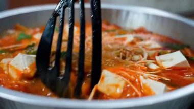 Tencerede kimchi çorbası kaynatılıyor ve spatulayla karıştırılıyor. Yüksek kalite 4k görüntü