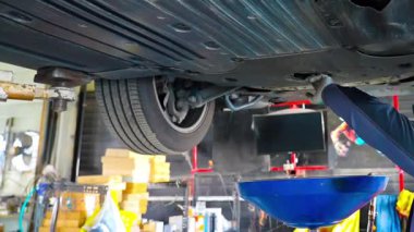 Yağ değişimi sırasında arabanın altındaki eski kirli yağ boşaltılıyor. Araba motorunun alt görüntüsü. Motor yağını değiştiriyorum. Yüksek kalite 4k görüntü