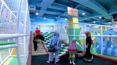 Çocuklar ve ebeveynleri kapalı oyun alanında ve oyun istasyonunda oynamaktan zevk alıyorlar. Bandung, 9 Temmuz 2025