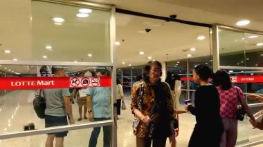 Alışveriş merkezinin girişindeki bir sıra insan, yürüyen merdivenle alışveriş alanına gidiyor. Bandung 25 Haziran 2025