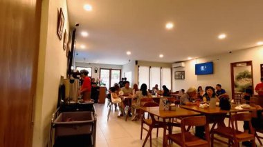 Bandung şehrindeki modern bir restoranın hareketli atmosferinde bir sürü müşteri geliyor ve garsonlar siparişlerle meşgul. Bandung 8 Temmuz 2025