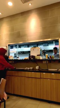 Restoran personeli müşterilerin siparişlerini hazırlamakla meşgul. İnsanlar modern bir restoranda arkadaşları ve ailesiyle öğle yemeği yemekten hoşlanırlar. Bandung, 2 Haziran 2025