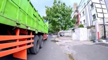 5 Nisan 2025 'te, Bandung, Batı Java, Endonezya' daki iş yerlerine giderken, güneşli bir kavşakta motosiklet ve araba sürenlerin 4K kaydı.