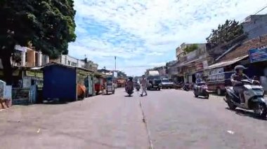 Kalabalık şehir manzarasını gösteren 4K görüntüleri açık bir günde birçok insanın motosiklet sürdüğü ve araba sürdüğü, Bandung, West Java, Endonezya 5 Nisan 2025.