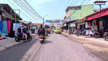 Kalabalık şehir manzarasını gösteren 4K görüntüleri açık bir günde birçok insanın motosiklet sürdüğü ve araba sürdüğü, Bandung, West Java, Endonezya 5 Nisan 2025.