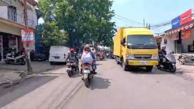 Kalabalık şehir manzarasını gösteren 4K görüntüleri açık bir günde birçok insanın motosiklet sürdüğü ve araba sürdüğü, Bandung, West Java, Endonezya 5 Nisan 2025.