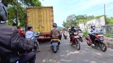 Kalabalık şehir manzarasını gösteren 4K görüntüleri açık bir günde birçok insanın motosiklet sürdüğü ve araba sürdüğü, Bandung, West Java, Endonezya 5 Nisan 2025.