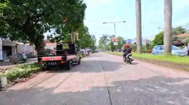 Kalabalık şehir manzarasını gösteren 4K görüntüleri açık bir günde birçok insanın motosiklet sürdüğü ve araba sürdüğü, Bandung, West Java, Endonezya 5 Nisan 2025.