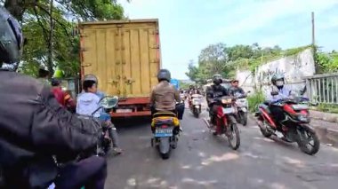 Kalabalık şehir manzarasını gösteren 4K görüntüleri açık bir günde birçok insanın motosiklet sürdüğü ve araba sürdüğü, Bandung, West Java, Endonezya 5 Nisan 2025.