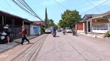 Kalabalık şehir manzarasını gösteren 4K görüntüleri açık bir günde birçok insanın motosiklet sürdüğü ve araba sürdüğü, Bandung, West Java, Endonezya 5 Nisan 2025.