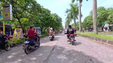 Kalabalık şehir manzarasını gösteren 4K görüntüleri açık bir günde birçok insanın motosiklet sürdüğü ve araba sürdüğü, Bandung, West Java, Endonezya 5 Nisan 2025.