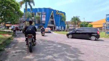 Kalabalık şehir manzarasını gösteren 4K görüntüleri açık bir günde birçok insanın motosiklet sürdüğü ve araba sürdüğü, Bandung, West Java, Endonezya 5 Nisan 2025.