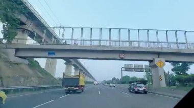 Kalabalık şehir manzarasını gösteren 4K görüntüleri açık bir günde birçok insanın motosiklet sürdüğü ve araba sürdüğü, Bandung, West Java, Endonezya 5 Nisan 2025.