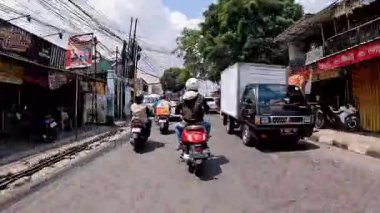 4K sinematik görüntüler Bandung 'un hareketli caddelerini yakalıyor, güneşli bir günde, Bandung, Batı Java, Endonezya 5 Nisan 2025' de, gidip gelen insanları gösteriyor..