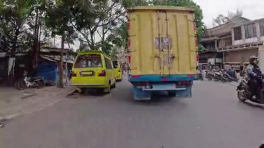 4K sinematik görüntüler Bandung 'un hareketli caddelerini yakalıyor, güneşli bir günde, Bandung, Batı Java, Endonezya 5 Nisan 2025' de, gidip gelen insanları gösteriyor..