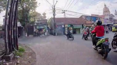 4K sinematik görüntüler Bandung 'un hareketli caddelerini yakalıyor, güneşli bir günde, Bandung, Batı Java, Endonezya 5 Nisan 2025' de, gidip gelen insanları gösteriyor..