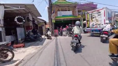 4K sinematik görüntüler Bandung 'un hareketli caddelerini yakalıyor, güneşli bir günde, Bandung, Batı Java, Endonezya 5 Nisan 2025' de, gidip gelen insanları gösteriyor..