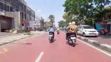 4K sinematik görüntüler Bandung 'un hareketli caddelerini yakalıyor, güneşli bir günde, Bandung, Batı Java, Endonezya 5 Nisan 2025' de, gidip gelen insanları gösteriyor..