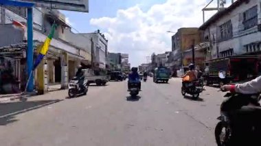 4K sinematik görüntüler Bandung 'un hareketli caddelerini yakalıyor, güneşli bir günde, Bandung, Batı Java, Endonezya 5 Nisan 2025' de, gidip gelen insanları gösteriyor..