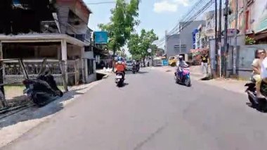 4K sinematik görüntüler Bandung 'un hareketli caddelerini yakalıyor, güneşli bir günde, Bandung, Batı Java, Endonezya 5 Nisan 2025' de, gidip gelen insanları gösteriyor..