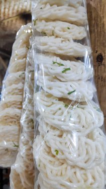 Markette satılık plastik torbalarda asılı çiğ, beyaz, spiral şekilli kerupuk krakerlerinin fotoğrafını kapat..