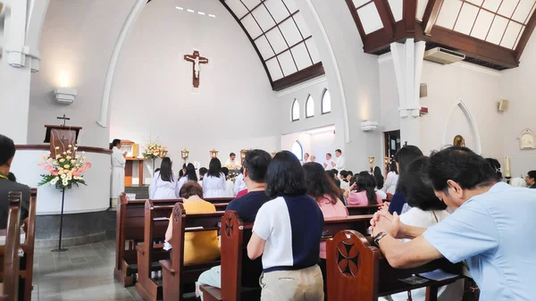Kilise sıralarında oturan insanlarla dolu bir ayin sırasında modern bir Katolik kilisesinin detaylı bir fotoğrafı. Bandung 7 Aralık 2025