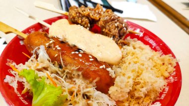 Popüler Japon sokak yemeği kombinasyonu fotoğrafı, tavuk yakitori veya katsu ve kremalı sosis, kıtır kıtır kızarmış kırıntılarla servis ediliyor..