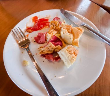 Kahvaltı için iştah açıcı sosisli sandviçin yakın plan fotoğrafı. Kahvehanedeki ahşap masada çatal ve bıçakla servis ediliyor..