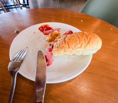 Kahvaltı için iştah açıcı sosisli sandviçin yakın plan fotoğrafı. Kahvehanedeki ahşap masada çatal ve bıçakla servis ediliyor..