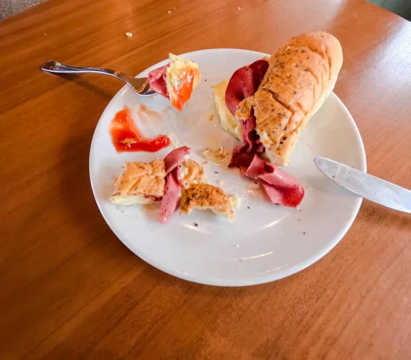 Kahvaltı için iştah açıcı sosisli sandviçin yakın plan fotoğrafı. Kahvehanedeki ahşap masada çatal ve bıçakla servis ediliyor..