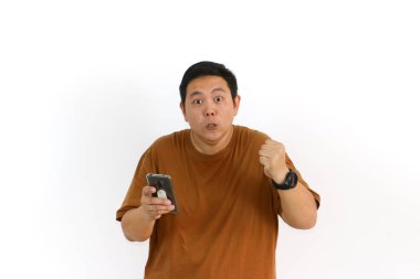 Kızgın bir Asyalı bağırıyor ve beyaz bir arka planda cep telefonu ekranını işaret ediyor..